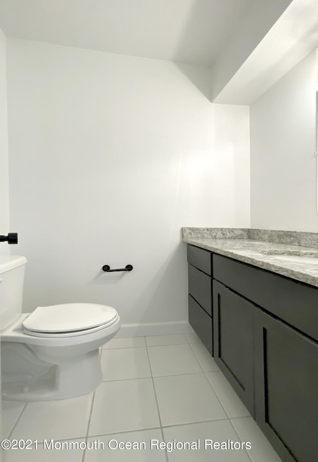 half bath with tile patterned flooring, vanity, toilet, and baseboards