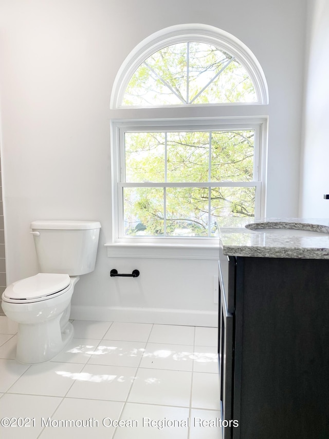 bathroom with toilet, vanity, baseboards, and tile patterned floors