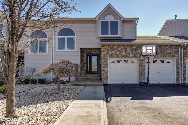 view of front of house featuring a garage, stone siding, and aphalt driveway