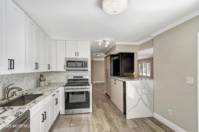 kitchen with light wood-style flooring, stainless steel appliances, a sink, backsplash, and crown molding