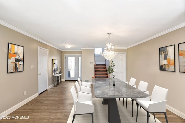 dining space featuring french doors, a notable chandelier, stairway, and wood finished floors