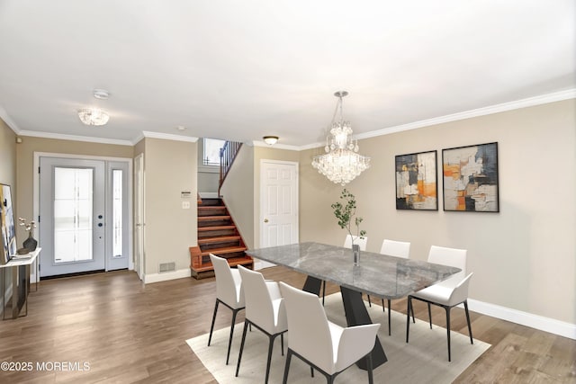 dining space with crown molding, stairway, a chandelier, and wood finished floors