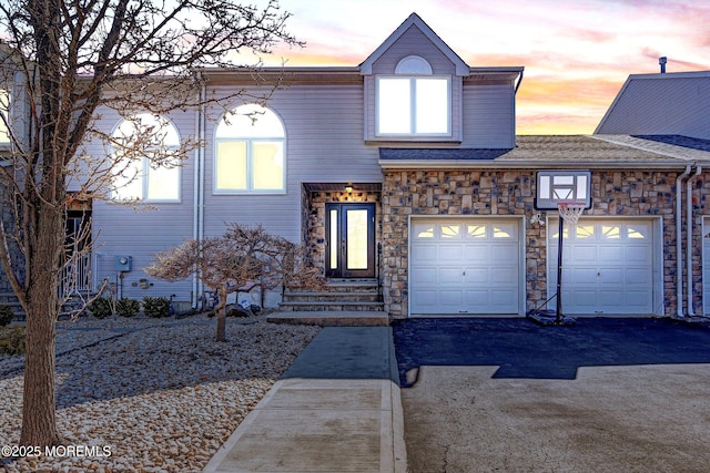 view of front of home with a garage, driveway, and stone siding