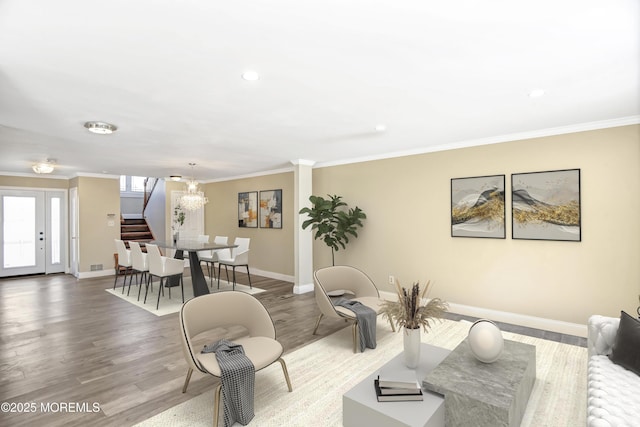 living room with a notable chandelier, baseboards, crown molding, and wood finished floors