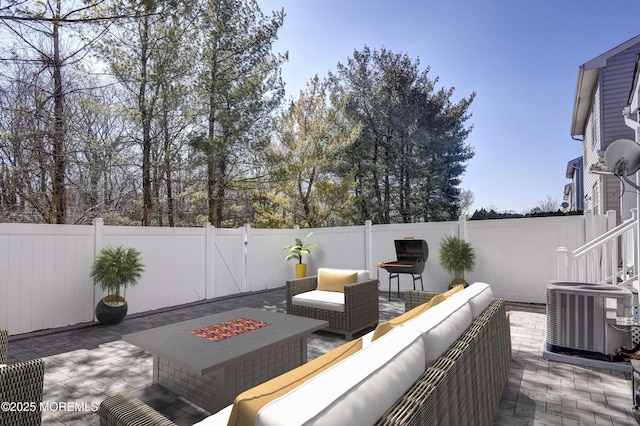 wooden terrace featuring an outdoor living space with a fire pit, a fenced backyard, a patio area, and cooling unit