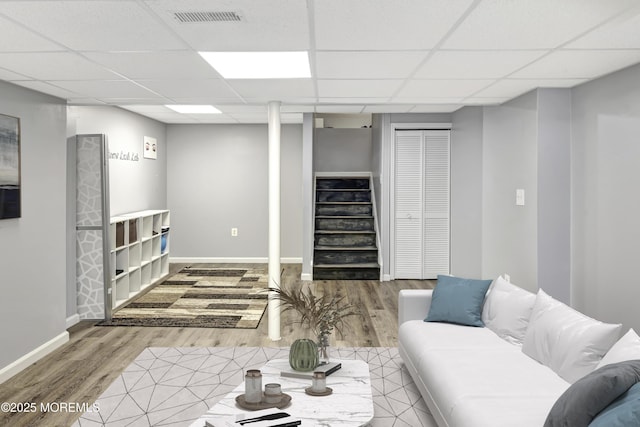 living area featuring stairs, visible vents, a drop ceiling, and wood finished floors