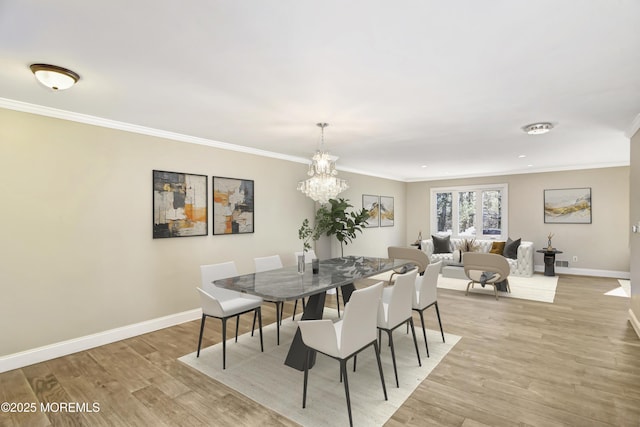 dining space featuring crown molding, light wood-style flooring, and baseboards