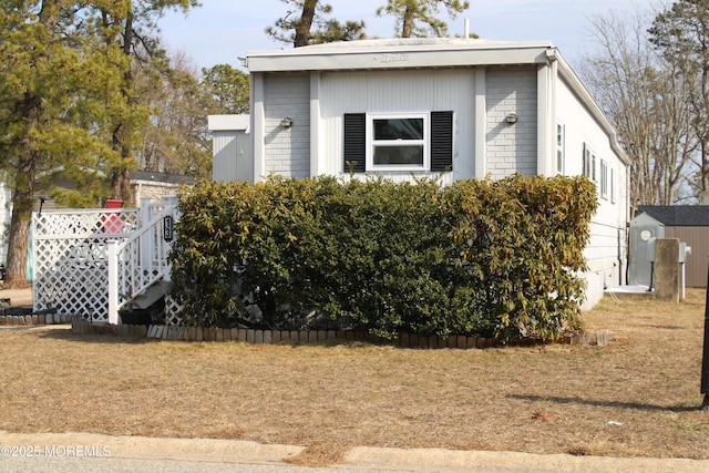 view of property exterior featuring an outbuilding, brick siding, and a storage unit