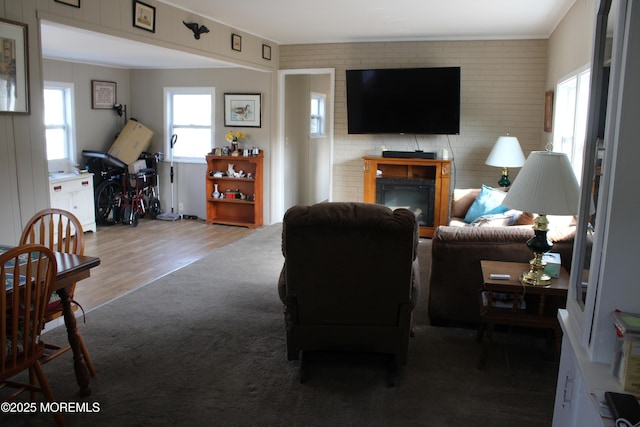 living area featuring a fireplace, brick wall, and wood finished floors