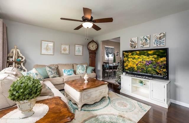 living area featuring ceiling fan, baseboards, and wood finished floors