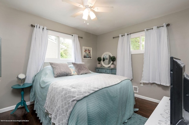 bedroom featuring ceiling fan, multiple windows, baseboards, and wood finished floors