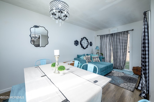 dining space featuring a notable chandelier, baseboards, and wood finished floors