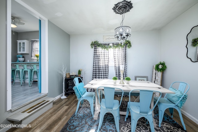 dining area featuring ceiling fan with notable chandelier, baseboards, and wood finished floors