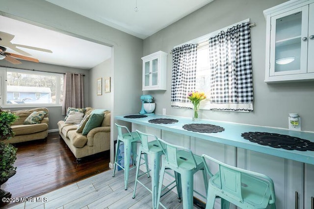 kitchen featuring glass insert cabinets, white cabinetry, ceiling fan, and wood finished floors