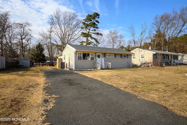 ranch-style house with central AC, aphalt driveway, and a front lawn