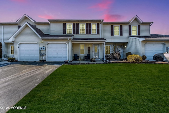 multi unit property with driveway, a garage, a porch, and a front yard