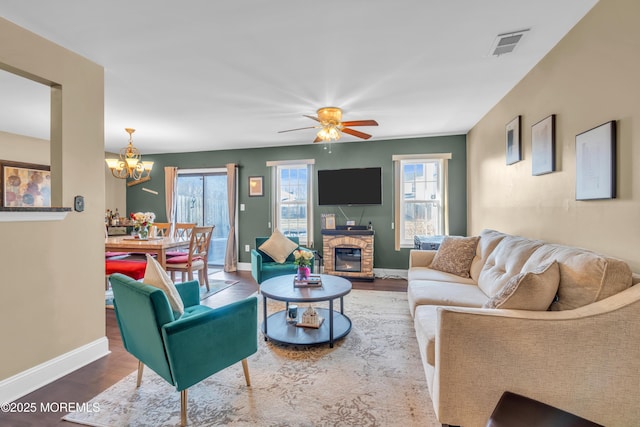 living area with a stone fireplace, a wealth of natural light, wood finished floors, and visible vents