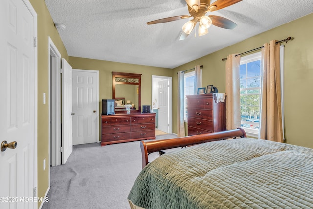 bedroom with light colored carpet, ceiling fan, and a textured ceiling