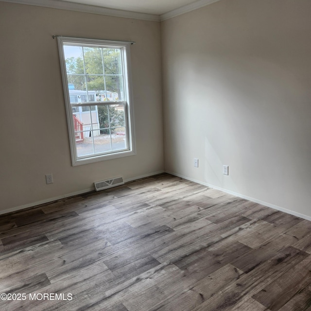 unfurnished room with ornamental molding, visible vents, baseboards, and wood finished floors