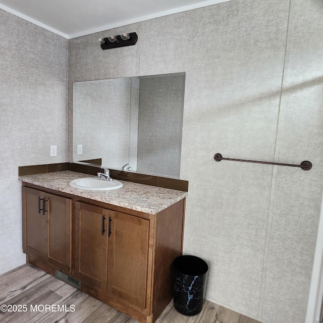 bathroom featuring visible vents, wood finished floors, vanity, and crown molding