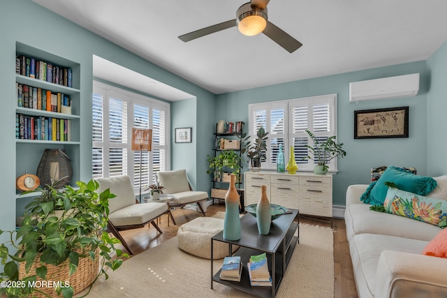 sitting room with a baseboard radiator, ceiling fan, wood finished floors, and a wall mounted air conditioner