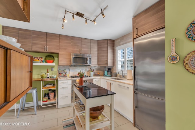 kitchen featuring light tile patterned floors, stainless steel appliances, a sink, and open shelves