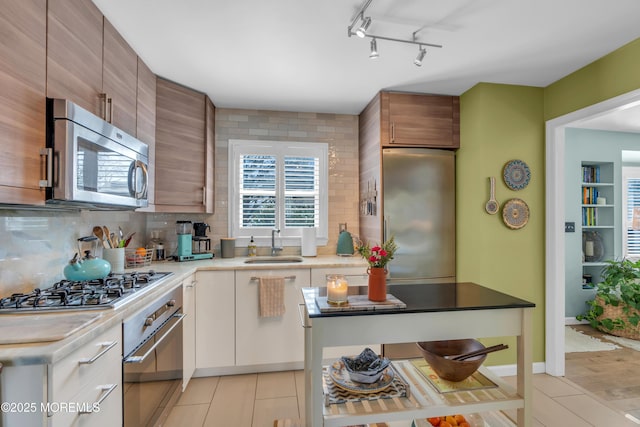 kitchen featuring light tile patterned floors, stainless steel appliances, a sink, light countertops, and tasteful backsplash