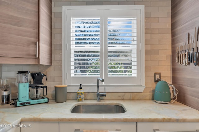 kitchen with light stone countertops, backsplash, and a sink