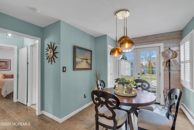 dining room featuring french doors, light wood finished floors, a baseboard radiator, and baseboards