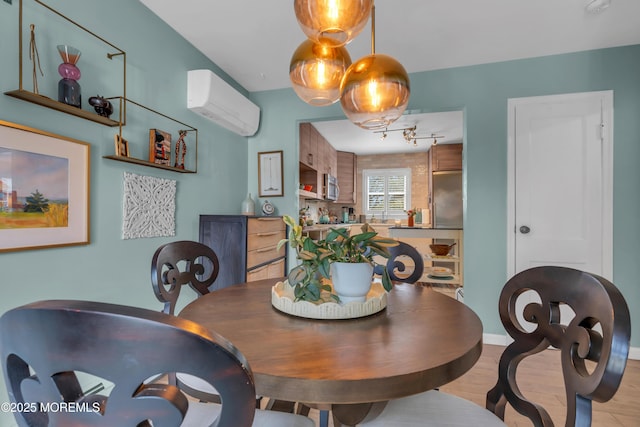 dining space featuring light wood-style floors, track lighting, and an AC wall unit