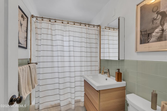 bathroom with curtained shower, tile walls, toilet, and vanity