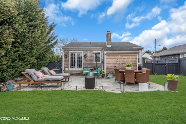 rear view of house featuring a lawn, a chimney, fence, french doors, and a patio area