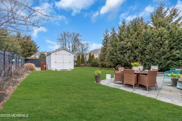 view of yard with a fenced backyard, outdoor dining area, an outdoor structure, a patio area, and a shed