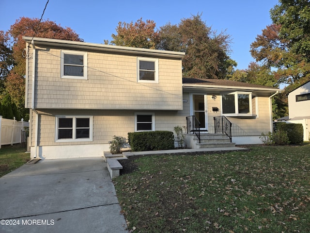 split level home with a front lawn and fence