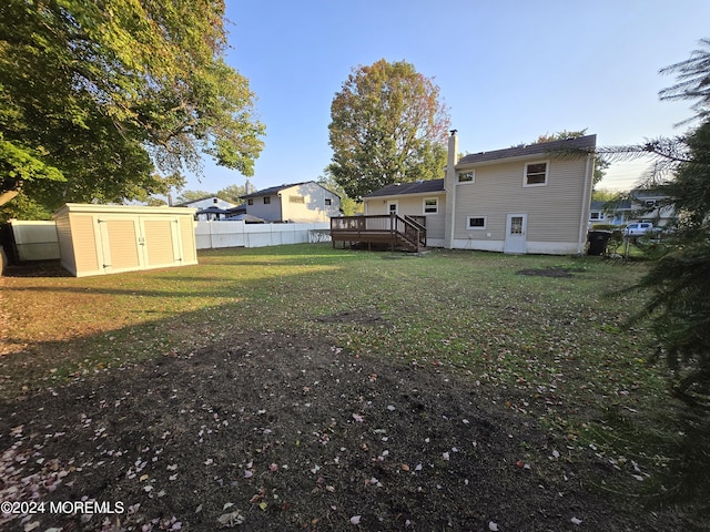 view of yard featuring an outbuilding, a shed, a fenced backyard, and a wooden deck