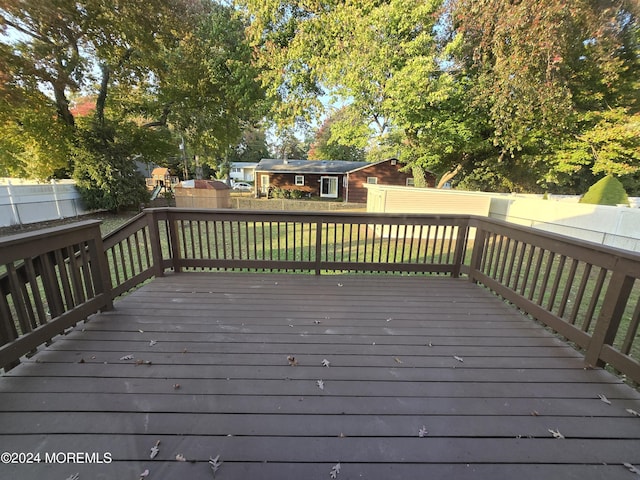 deck featuring a yard, a fenced backyard, and an outdoor structure