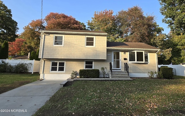 tri-level home with a front yard and fence