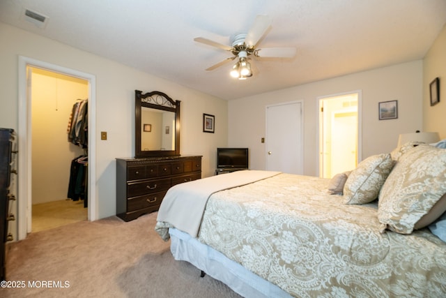 bedroom featuring light carpet, visible vents, a ceiling fan, a closet, and a walk in closet