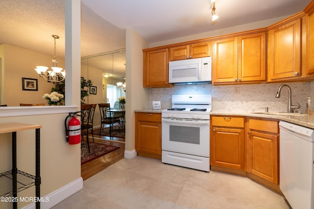 kitchen with white appliances, decorative backsplash, a sink, and an inviting chandelier