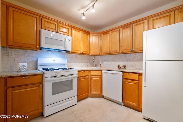 kitchen featuring light stone counters, brown cabinets, decorative backsplash, a sink, and white appliances