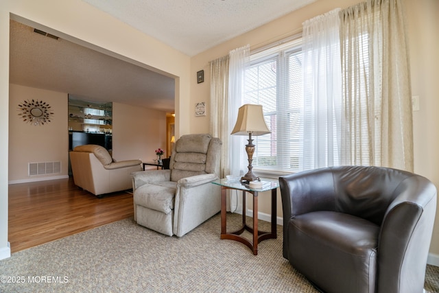 sitting room with wood finished floors, visible vents, and baseboards