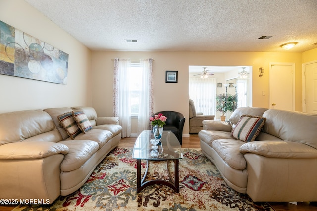 living room featuring a textured ceiling, visible vents, and wood finished floors