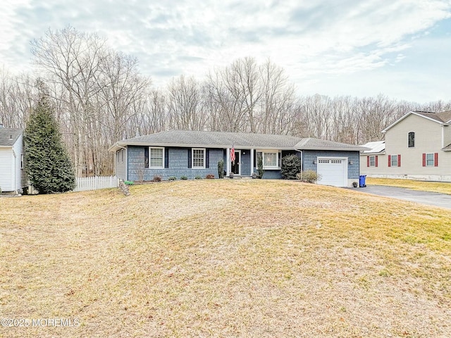 ranch-style house featuring a front yard, fence, driveway, and an attached garage