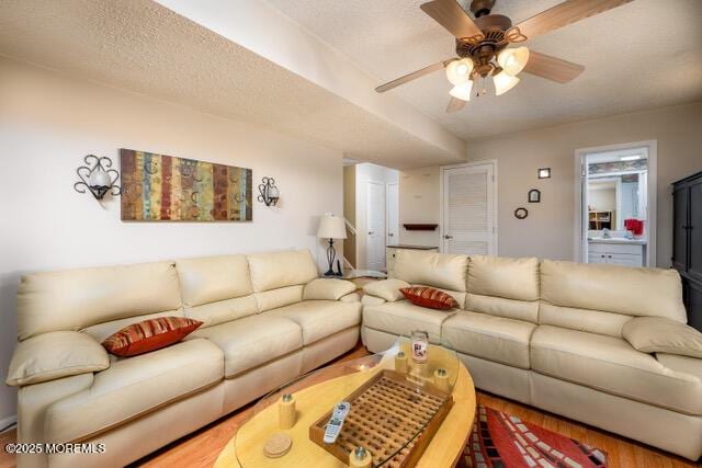 living area with a ceiling fan, a textured ceiling, and wood finished floors