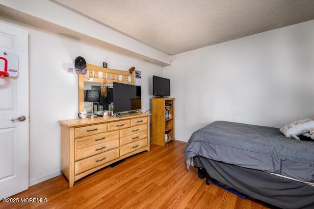 bedroom with light wood-style floors and a textured ceiling