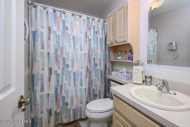 full bath with toilet, curtained shower, and vanity