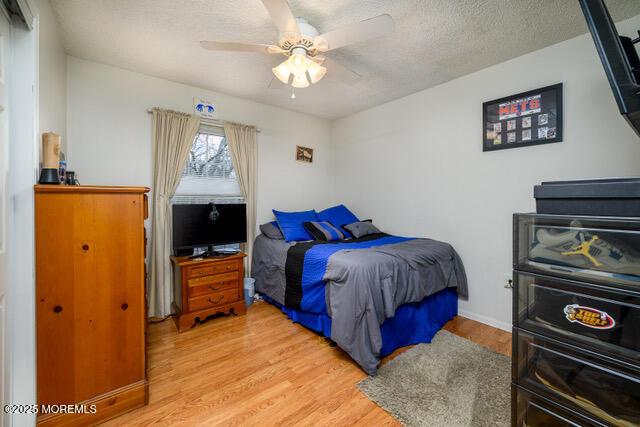 bedroom featuring a textured ceiling, ceiling fan, and light wood-style flooring