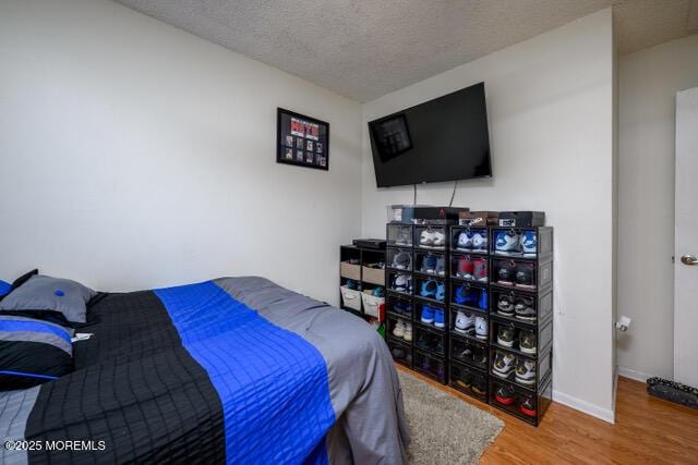 bedroom with a textured ceiling, baseboards, and wood finished floors