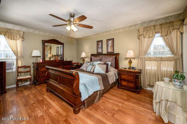 bedroom featuring a textured ceiling, a ceiling fan, and light wood-style floors