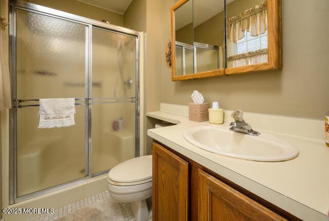 bathroom featuring vanity, tile patterned flooring, a shower stall, and toilet